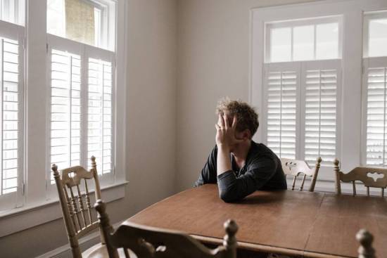 A man sits at a table with his head in his hand, illustrating the weight of discouragement.