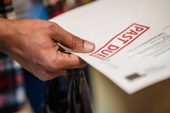 A person holds a Past Due notice in their hand