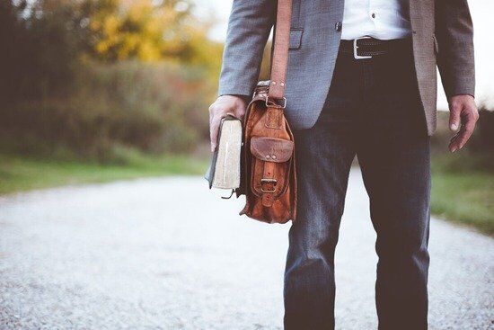 A man carries a leather satchel and Bible on his journey to spread the Gospel.