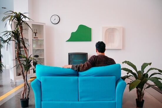 Man Watching Film A man sitting on his sofa, flipping through channels on his T.V.