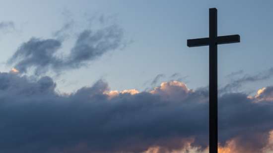 Cross Against Clouds Symbolizing Salvation A silhouetted cross against a sunset sky