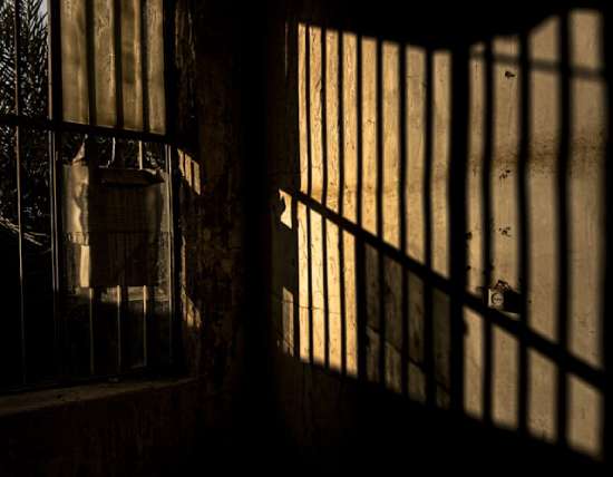 Prison Bars with Light Shining in A prison cell illuminated by light