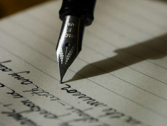 Old Pen Writing Paper A fountain pen writes on a piece of lined paper.