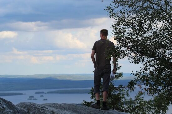 Man standing on a rock overlooking the ocean Forests and ocean landscapes are great places to visit for fresh air and relief from life's busyness.