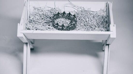 White manger A monochrome photograph of a king's crown lying in a manger filled with hay, representing the birth of our King and Savior, Jesus.