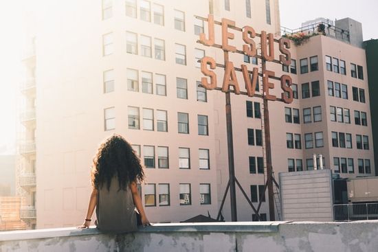 Girl looking at sign - Jesus Saves A girl sitting and looking at a sign that says Jesus Saves