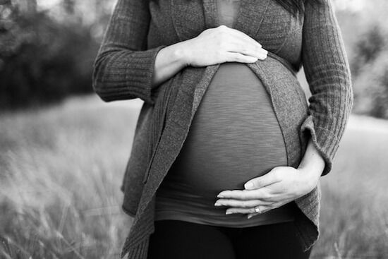 Praying for Child A pregnant woman with her hand on her belly, praying for her growing child