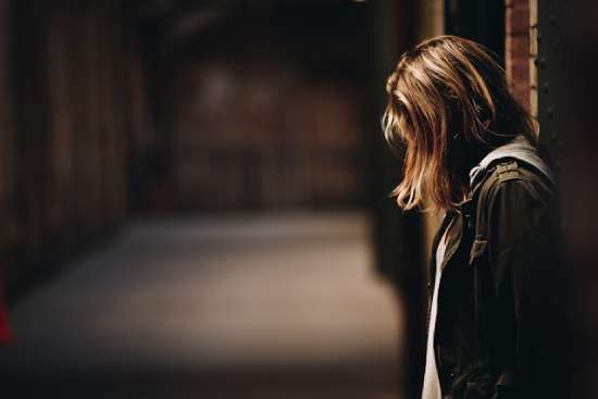 Woman Head Down Suffering A woman leaning against a wall and bowing her head in discouragement