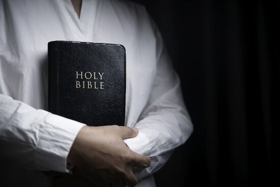 Woman Holding Her Bible Close A woman holding a Bible to her chest