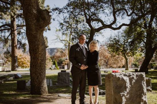 a young couple stands at a gravesite to pay their respects to a deceased loved one