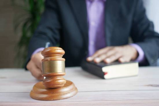 A man with one hand on a Bible and one hand hammering a gavel opens the discussion of the law-keeping in the Bible vs. legalism