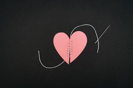 A split paper heart that's been stitched back together