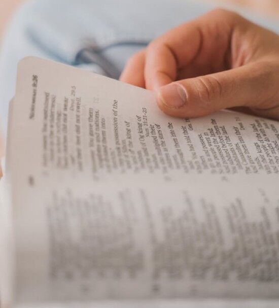 Hand holding the outside edge of an open Bible