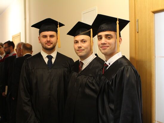 A group of theology students wearing graduation regalia at their graduation.