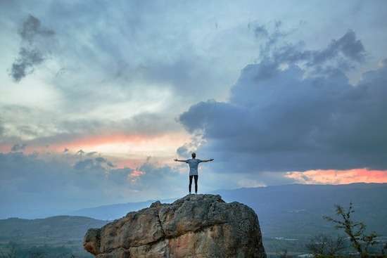 Transformed Man on Rock A man standing on a rock with arms outstretched