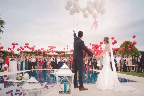 Wedding Ceremony A bride and groom release white balloons into the air at their wedding celebration as all their guests cheer.