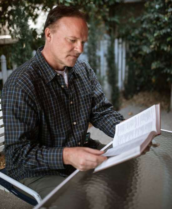 Man Reading Bible A man sitting in a chair and reading the Bible