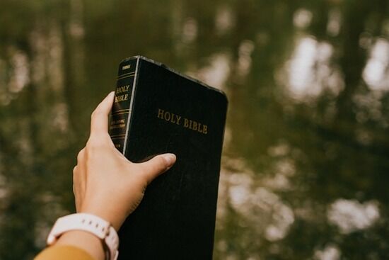 Person Holding Bible up A person holding a Bible
