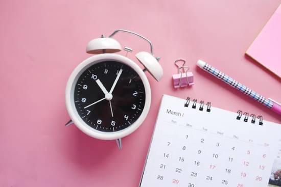 Analog Alarm Clock and Calendar on a Pink Surface An alarm clock next to a calendar represents our desire to know when Jesus will return—even though the Bible doesn't tell us the exact date.