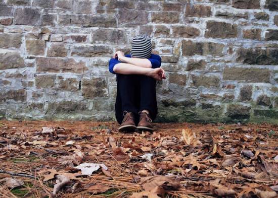 Hopeless person A discouraged person hunched against a wall, burying their face in their arms.