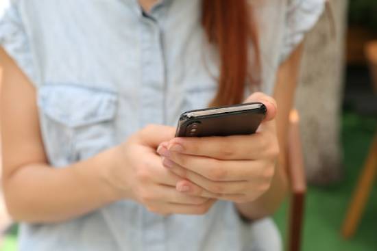 A woman looking at her smartphone, which is one way many of us can get our information.