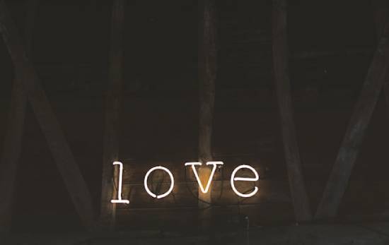 Four bright light bulbs spell out the word "love," each bulb in the shape of a letter.