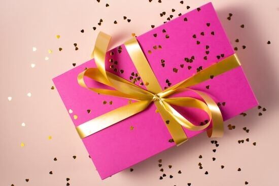 A bright pink gift box A bright pink gift box with a golden ribbon and confetti scattered around it, representing how the spirit of prophecy is a gift from God
