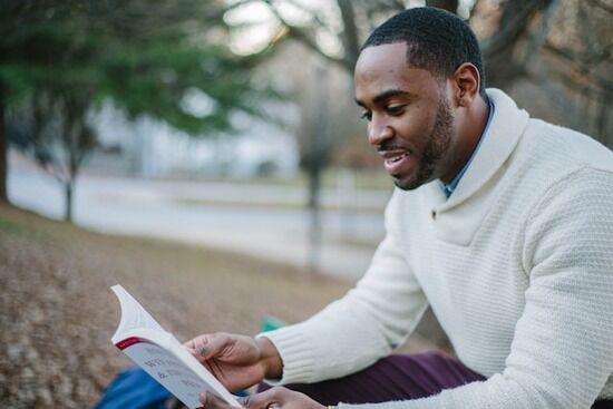 Reading Book A man sitting on a park bench and reading a devotional book