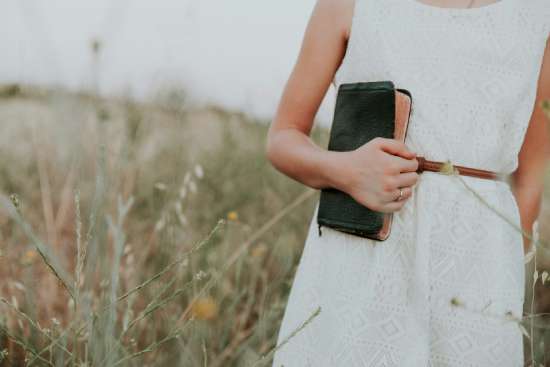 Woman in a field holding a bible