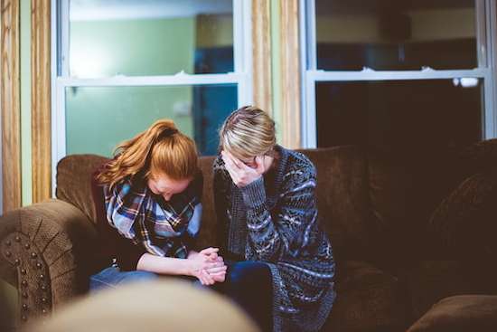 Two women praying together as they resolve past conflicts