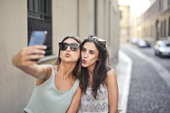 Two Women Taking a Selfie Two young women pursing their lips and posing for a selfie showing self love