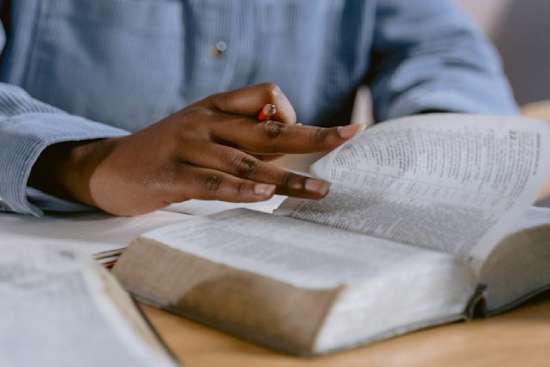 Woman reading her Bible A person flipping through a Bible, pencil in hand