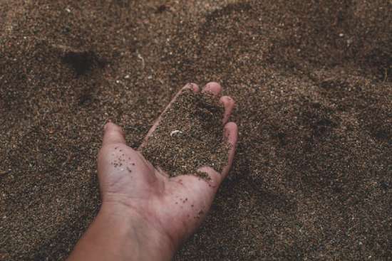 Hand Holding Sand A hand sifting through sand representing the dust that was used to create humankind.