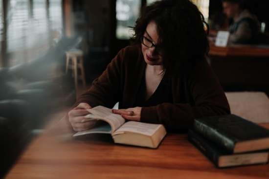 Woman Reading the Bible A woman studies the Bible at a wooden desk.