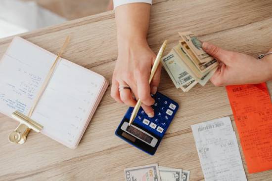 Person Holding Money while Using a Calculator to Determine Debt The image of someone calculating debt reminds us that the Bible principles about repaying and lending still apply to our lives today. And that if we're feeling trapped by financial circumstances, God won't leave us to figure it out alone.